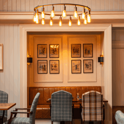 Elegant dining area at Dromoland Castle featuring plush seating and framed artwork, illuminated by a warm chandelier, creating a cosy ambience.