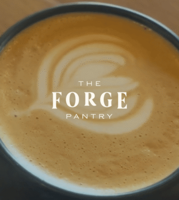 Enjoy a creamy latte with artistic foam at The Forge Pantry, perfect for a relaxing morning coffee.
