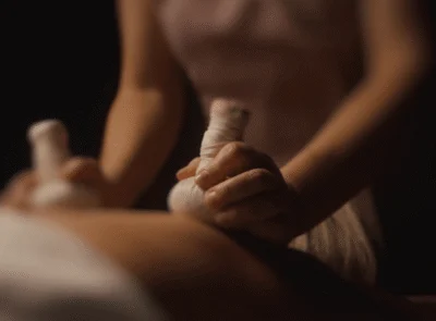 Relaxing spa massage with herbal pouches at luxury hotel, offering rejuvenation and wellness in serene surroundings.