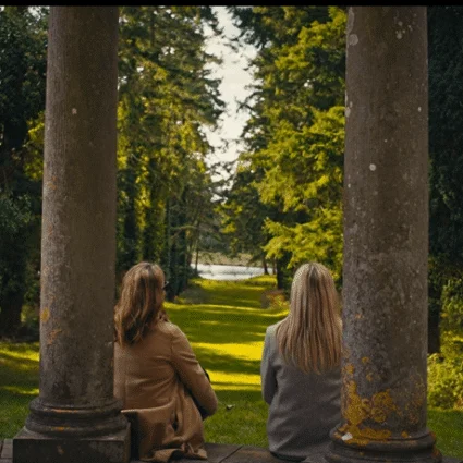Guests enjoying serene garden view from stone pavilion at luxury countryside hotel.