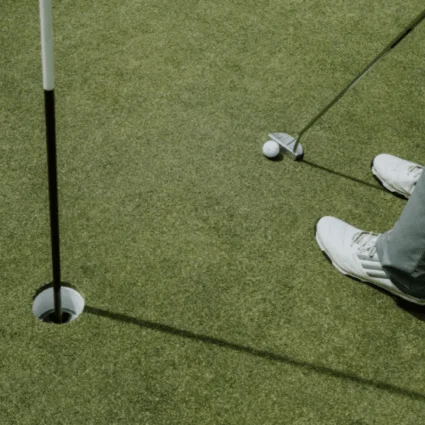 A golfer in white shoes prepares to putt on a pristine green at Dromoland Castle's championship golf course, showcasing precision and focus.
